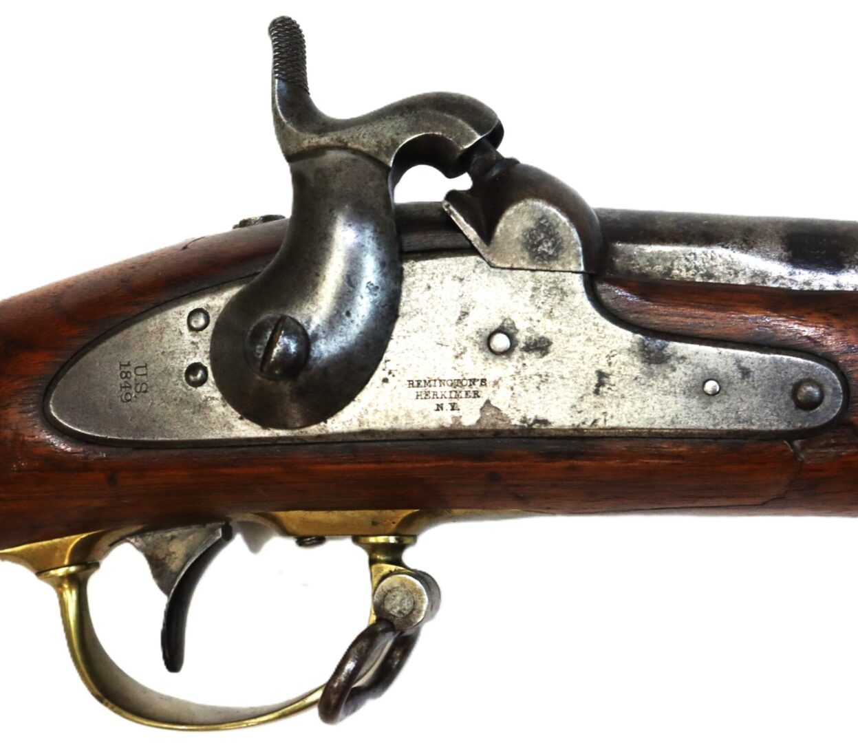 Close-up of a Remington Herkimer antique rifle's lock mechanism, featuring the metal plate, hammer, trigger, and wood stock. Metal components display visible markings and serial numbers.